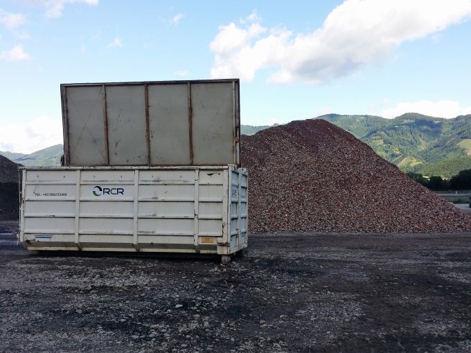 Baucontainer mit Deckel platziert vor einem Schutthaufen des Recycling Center Retznei 